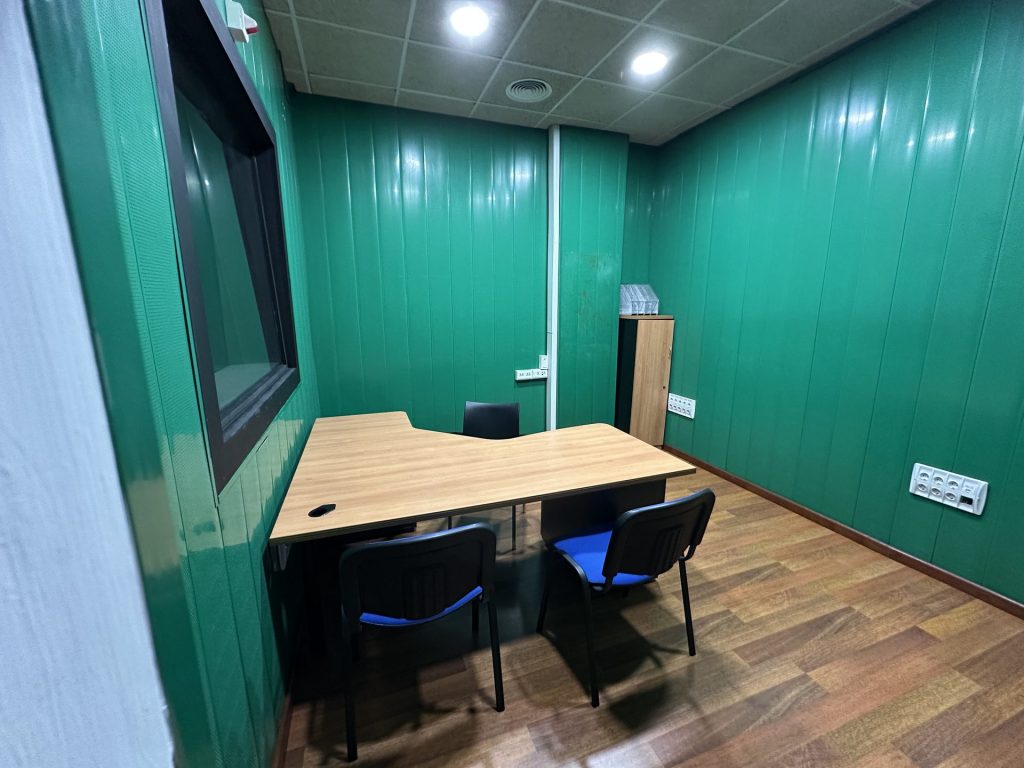 Oficina 5 privada con mesa en L y ventana a sala contigua