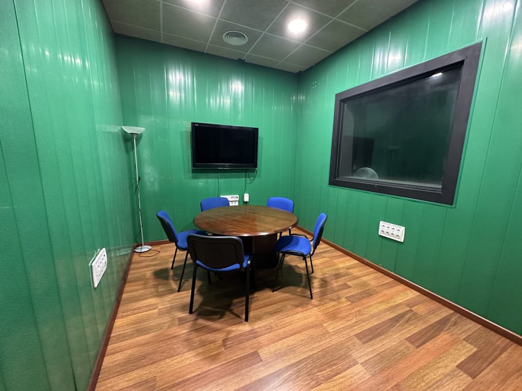 Sala de reuniones insonorizada con pantalla de gran formato para presentaciones, podcast y grabaciones