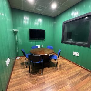 Sala de reuniones insonorizada con pantalla de gran formato para presentaciones, podcast y grabaciones